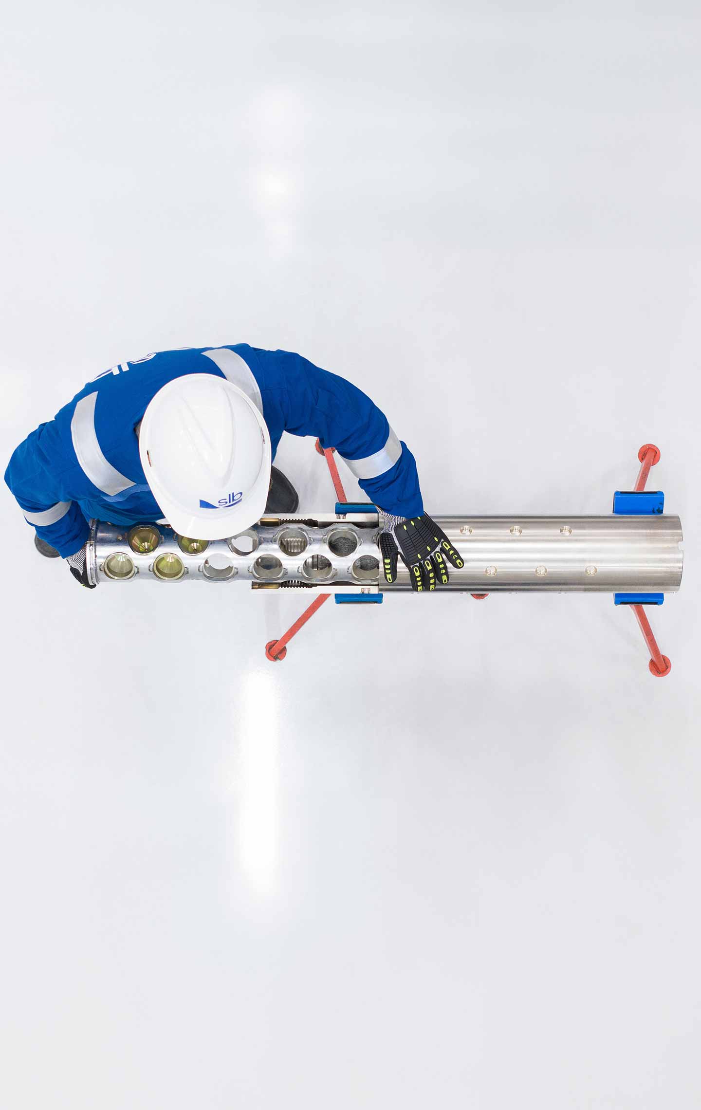 Top down aerial view of an SLB employee inspecting a tool