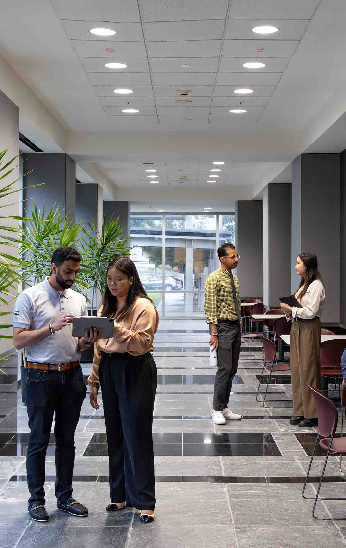 Employees conversing in groups of two in an office hallway