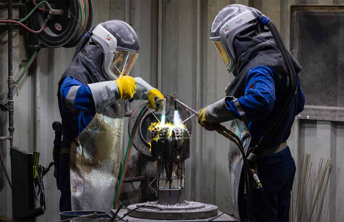 Two operators wearing full safety PPO welding a drill bit
