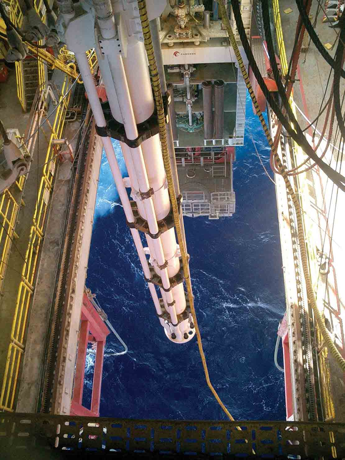 Riser being lowered in ocean from rig floor.