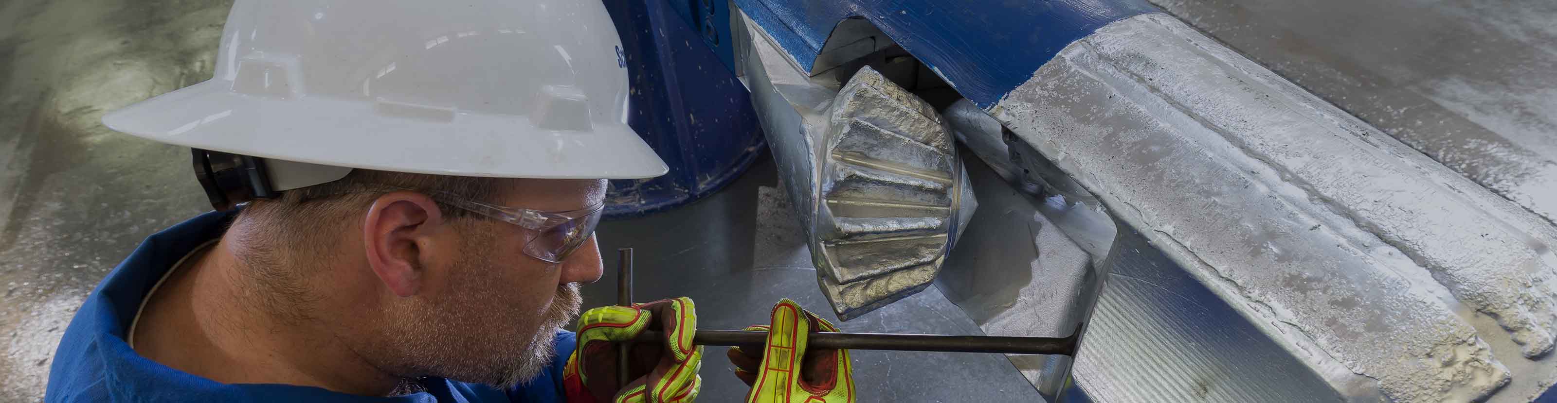 Schlumberger worker performing maintenance on an Reamaster-XTU forged cutter arm underreamer.