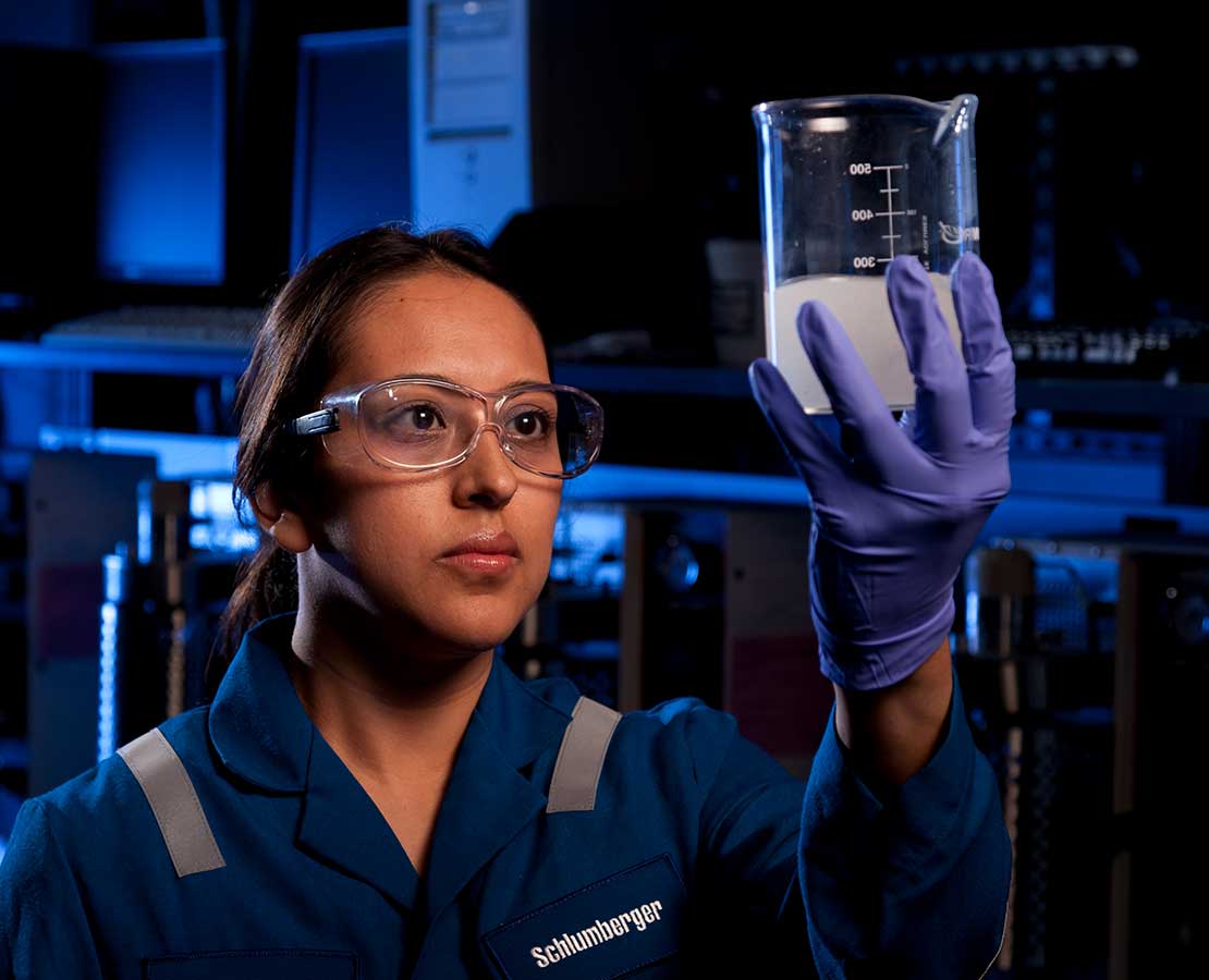 Schlumberger Lab Worker Looking at Fluid in Glass Beaker