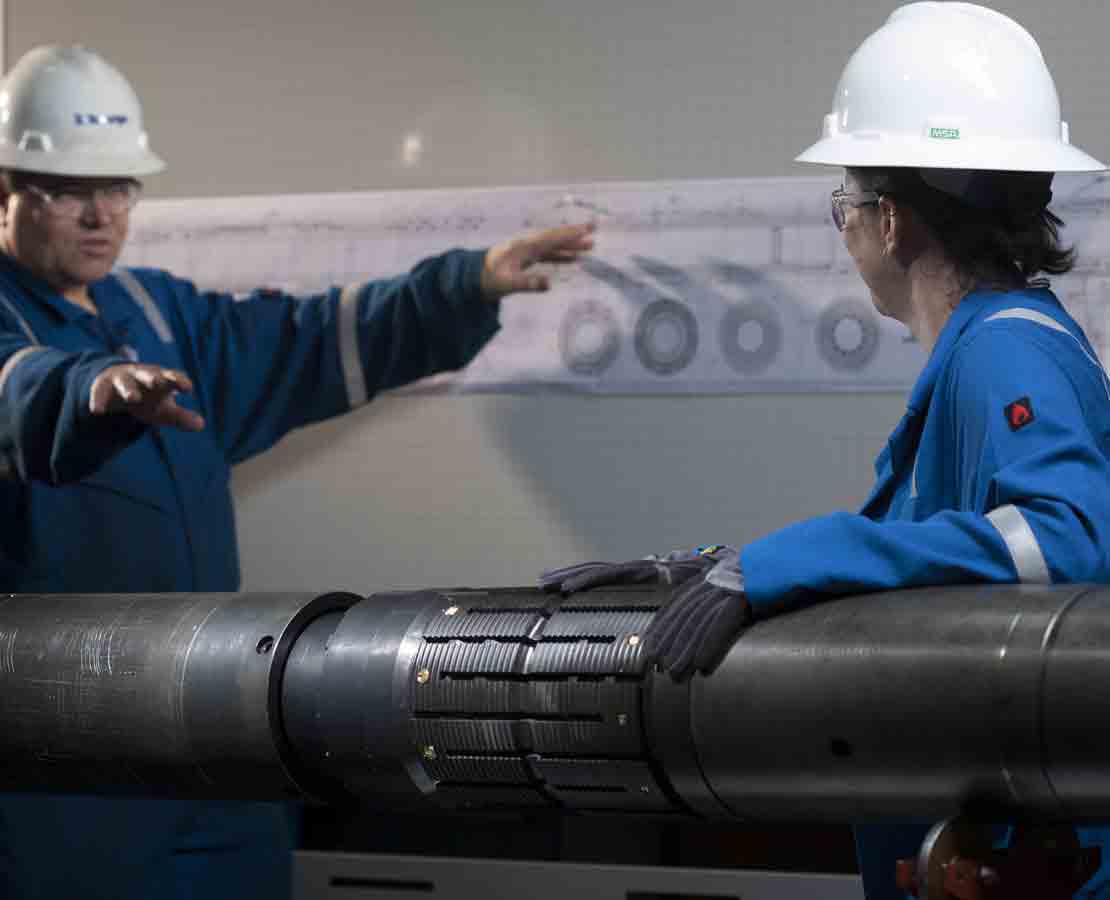 Two Schlumberger workers discussing the tool as part of the CERTIS high-integrity reservoir test isolation system.