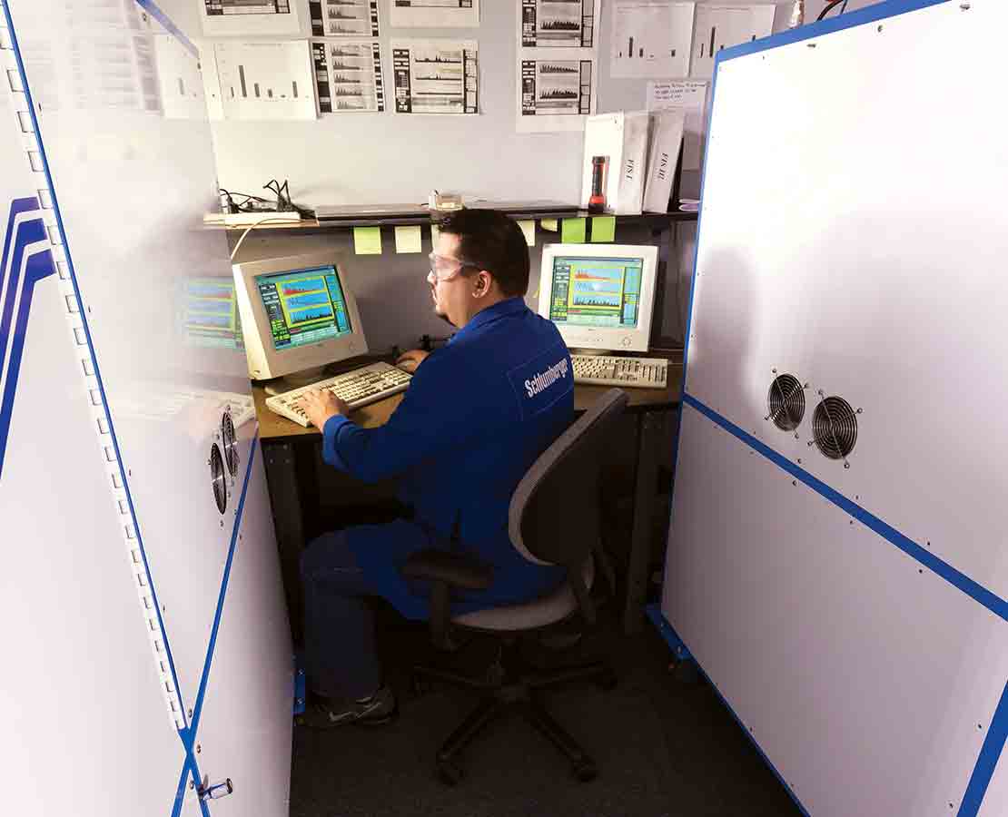 Schlumberger worker looking at two monitors as part of the fluid inclusion technology laboratory services.