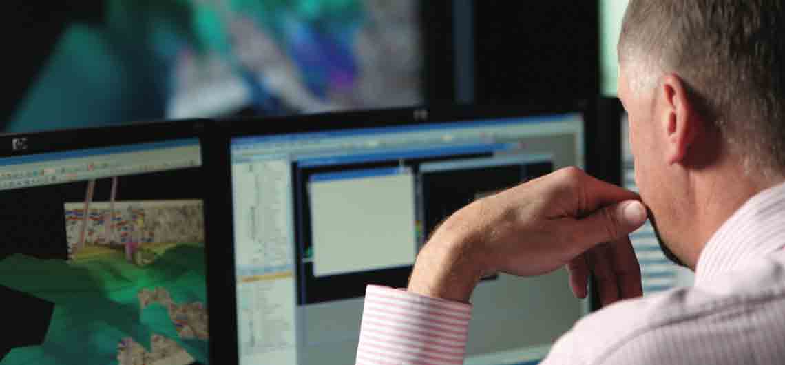 Schlumberger worker analyzing EOR measurements displayed on desktop monitors.